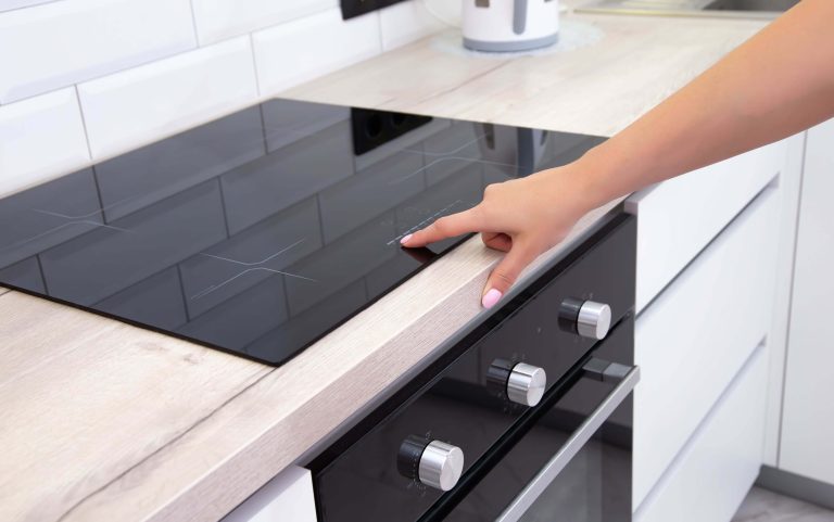 une femme montrant la distance exacte entre la plaque de cuisson et le bord du plan de travail qu'il faut respecter